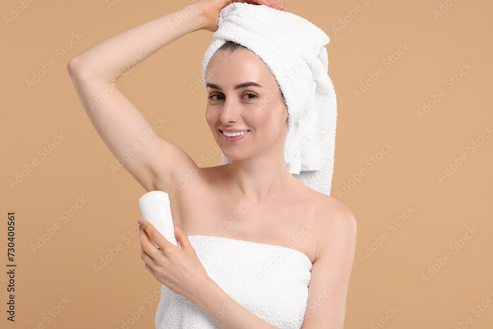 Beautiful woman applying deodorant on beige background Beautiful woman applying deodorant on beige background