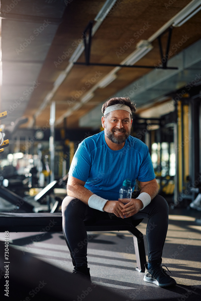 Happy mature athletic man resting during water break in gym and looking at camera. Happy mature athletic man resting during water break in gym and looking at camera.