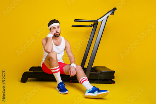 Fototapeta Naklejka Na Ścianę i Meble -  Full length portrait of unsatisfied man sit treadmill brainstorming lack motivation empty space isolated on yellow color background