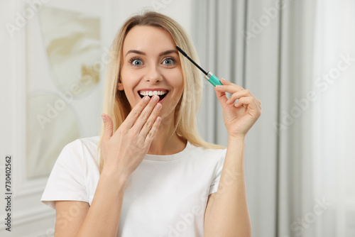 Beautiful happy woman with mascara at home