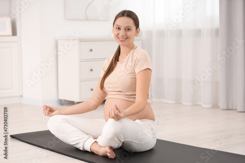 Pregnant woman meditating on yoga mat at home