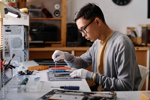 Bild auf Leinwand Professional repairman sitting at desk in workshop and repairing faulty smartpho
