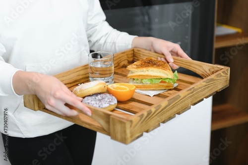 Young woman holding tray with breakfast food at home