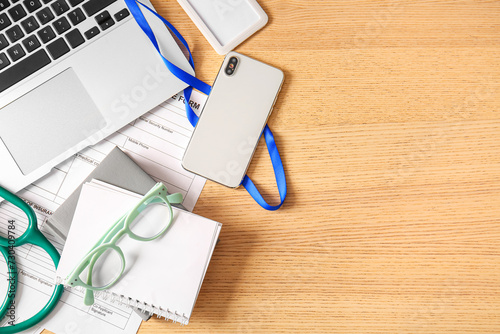 Mobile phone with laptop, eyeglasses and notebooks on wooden medical desk, to...