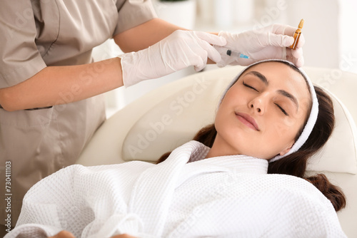 Beautiful young woman receiving injection in beauty salon, closeup