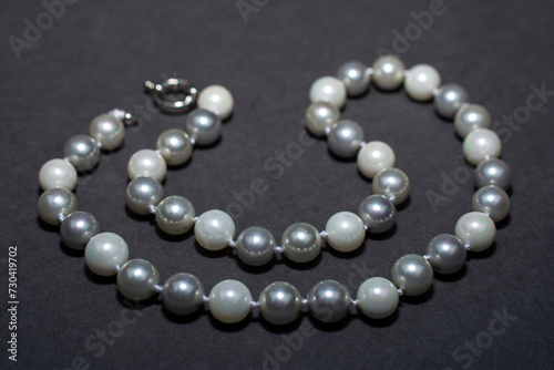 Pearl white round beads on a gray background. Women's elegant jewelry.