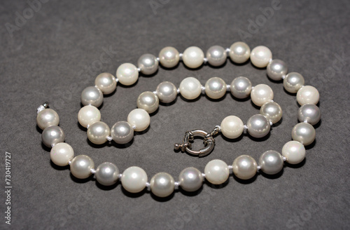 Pearl white round beads on a gray background. Women's elegant jewelry.