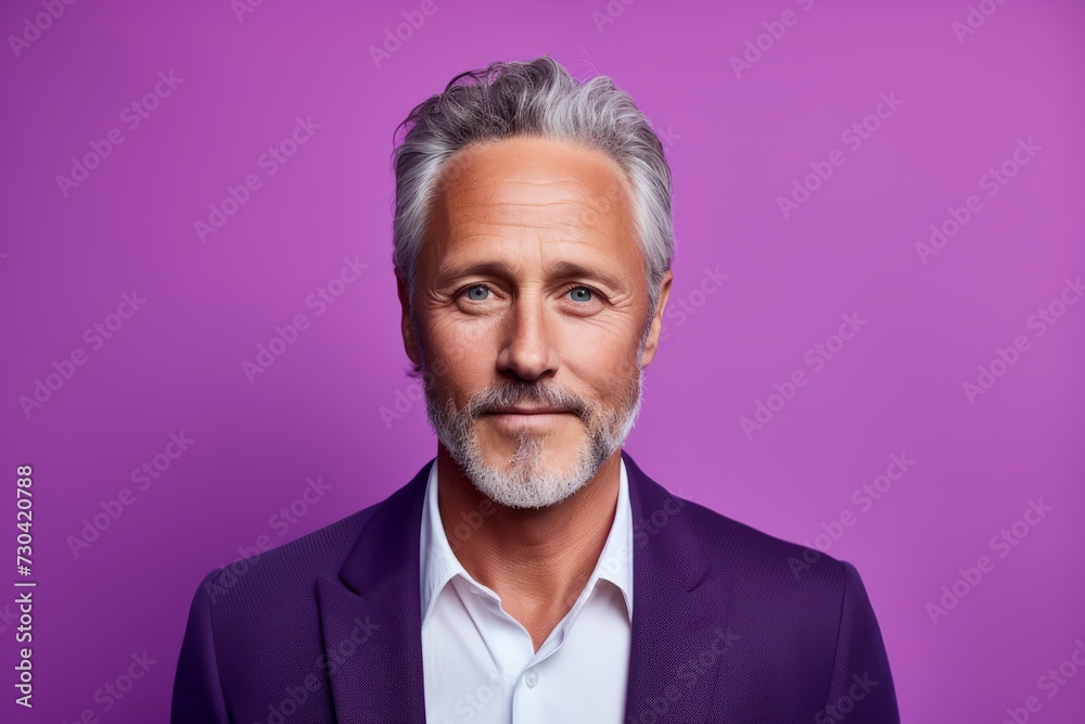 Portrait of handsome mature man with grey hair and beard. Isolated on purple background.