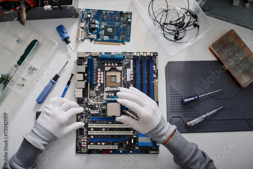 Unrecognizable electronic repairman holding CPU before placing it into PC mainboard socket photo