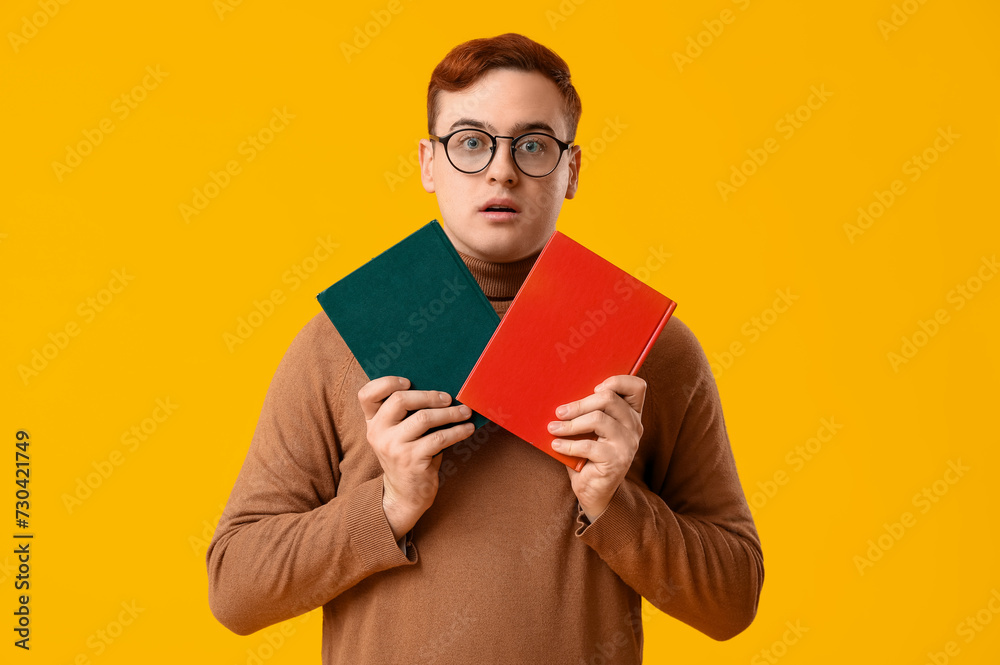 Emotional young man with books on yellow background Emotional young man with books on yellow background