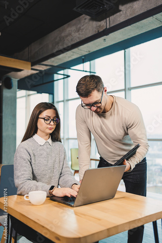 Working day in a modern office with workers in casual clothes, male and female colleagues working with a laptop on a modern project.