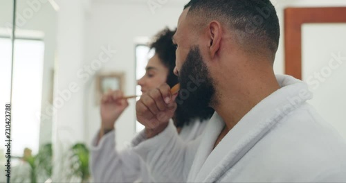 Couple, bathroom and brushing teeth for dental hygiene, care or morning routine together at home. Young man and woman with toothbrush for tooth whitening, grooming or getting ready in robes at house photo