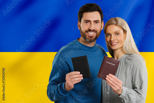 Immigration. Happy man and woman with passports against national flag of Ukraine, space for text photo