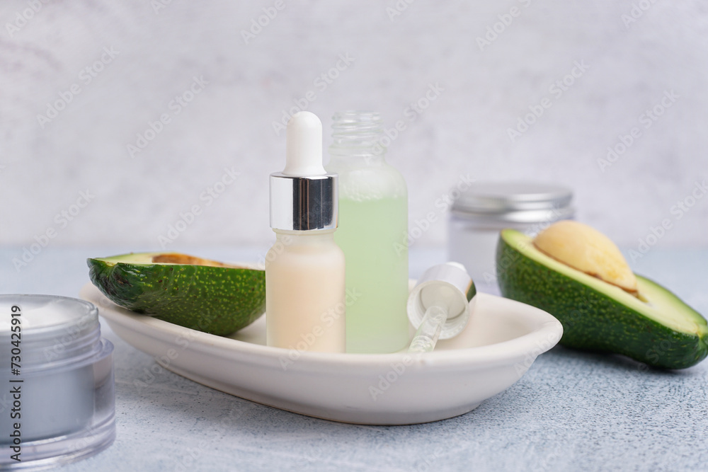 Fresh avocado and bottles of essential oil on light background, closeup Fresh avocado and bottles of essential oil on light background, closeup