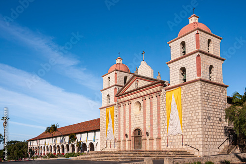 Santa Barbara, CA, USA - April 20, 2009: Old Mission church and white abbey facade with red roof under blue cloudscape.