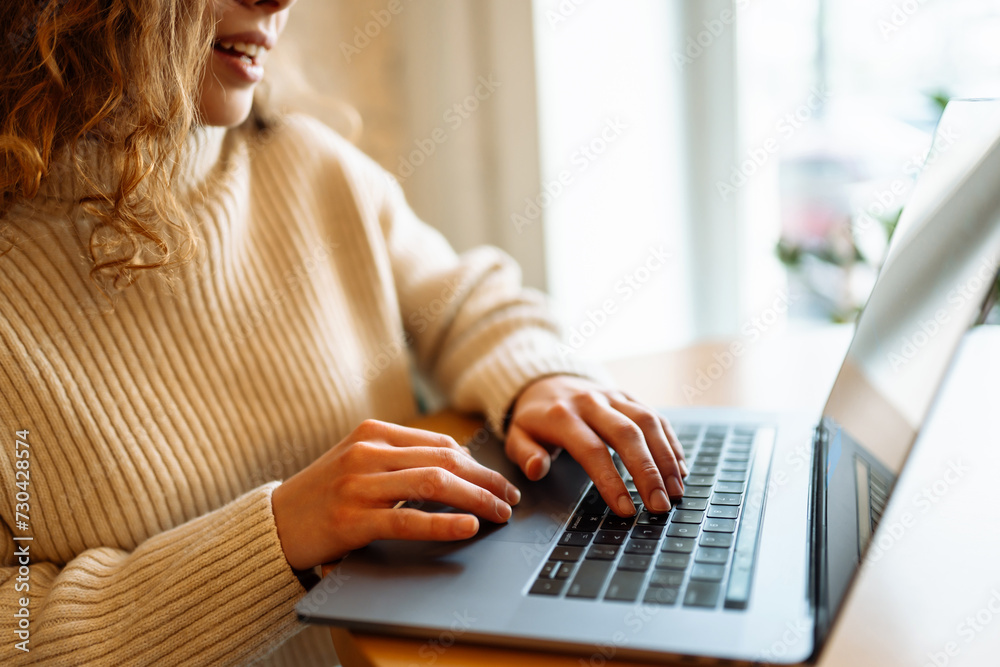 Fototapeta premium Close-up of hands working on a laptop keyboard. Home working and browsing concept in a cozy atmosphere. Freelance, online course. Shopping online. Cyber security concept