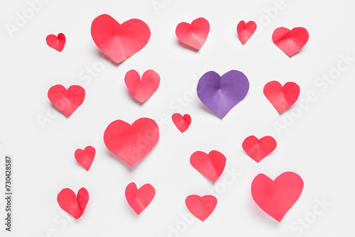Purple paper heart among red ones on light background. Valentines Day celebration