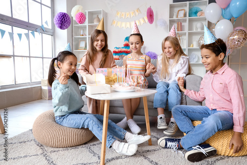 Cute little children in party hats with cake celebrating Birthday at home
