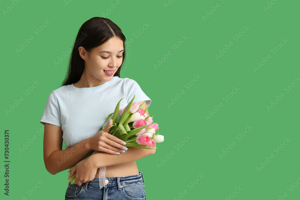Pretty young Asian woman with bouquet of beautiful tulips on green background. International Women's Day Pretty young Asian woman with bouquet of beautiful tulips on green background. International Women's Day