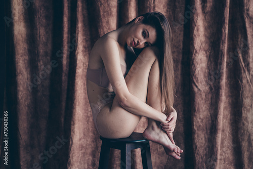 Photo with no retouch of gorgeous girl sit stool hug tender feet after spa procedure isolated studio background © deagreez