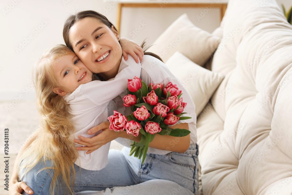 Little girl congratulating her mom with bouquet of flowers at home. Mother's Day celebration