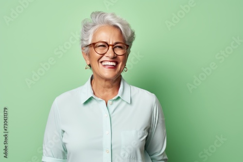 Portrait of happy senior woman with eyeglasses against green background