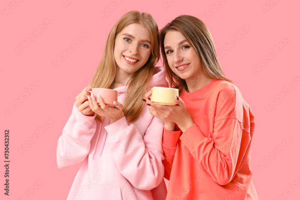 Beautiful young women with cups of tea on pink background Beautiful young women with cups of tea on pink background