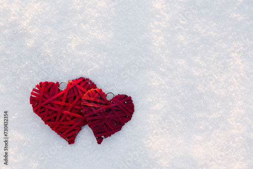 Happy valentines day background with two red hearts on white snow .