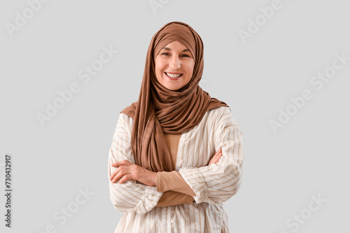 Mature Muslim woman in hijab on light background