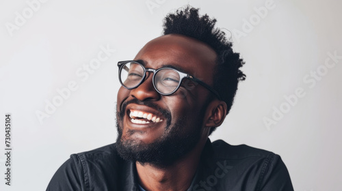 A joyful portrait of a Black man in glasses against a white backdrop. © ImageHeaven