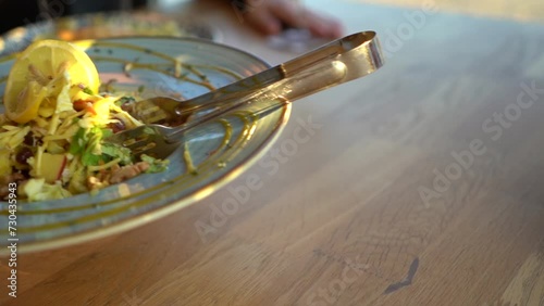 Close-up of placing a modern plate on the table with a fancy lemon salad, finely chopped various vegetables and spices. Lunch in a fancy restaurant