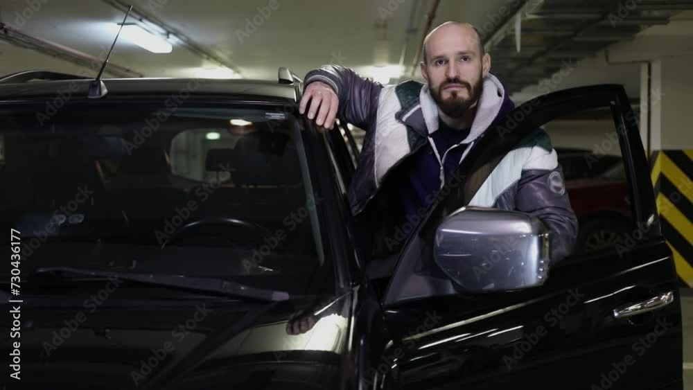 Man poses near opened drivers door of black car. Slow motion