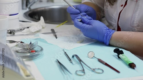  Hands of dentist which cleans implant by hook at table with other tools photo
