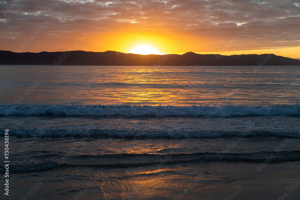 Sunset over Cape Reinga and the ocean in Spirits Bay, Northland, New Zealand.