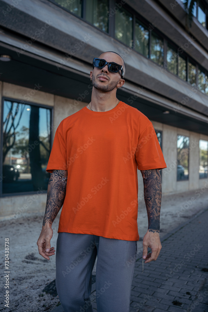 Hombre joven tatuado y musculoso posando con ropa urbana en la calle Hombre joven tatuado y musculoso posando con ropa urbana en la calle