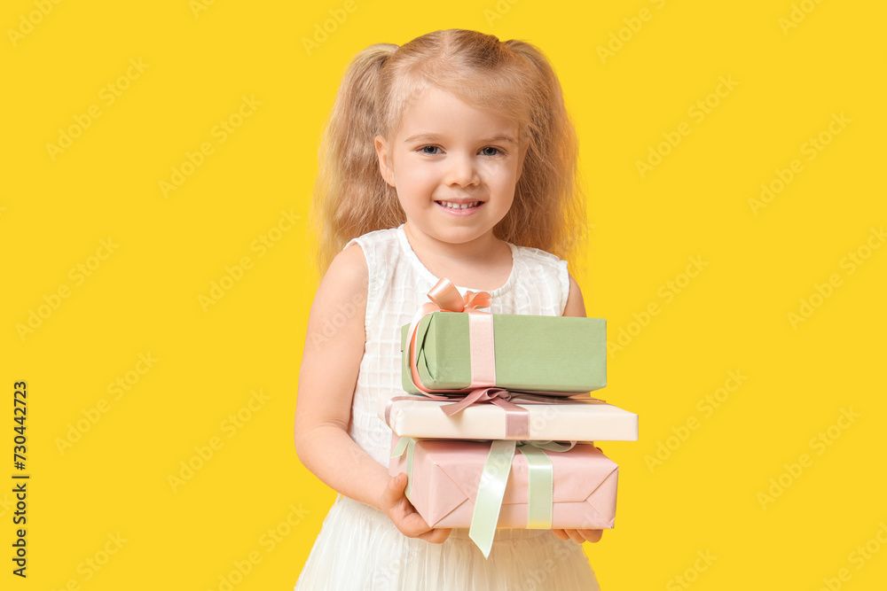 Cute little girl with gift boxes on yellow background. International Women's Day Cute little girl with gift boxes on yellow background. International Women's Day