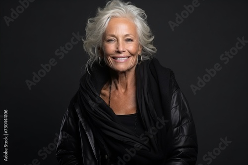 Portrait of a beautiful senior woman wearing a black jacket on a dark background