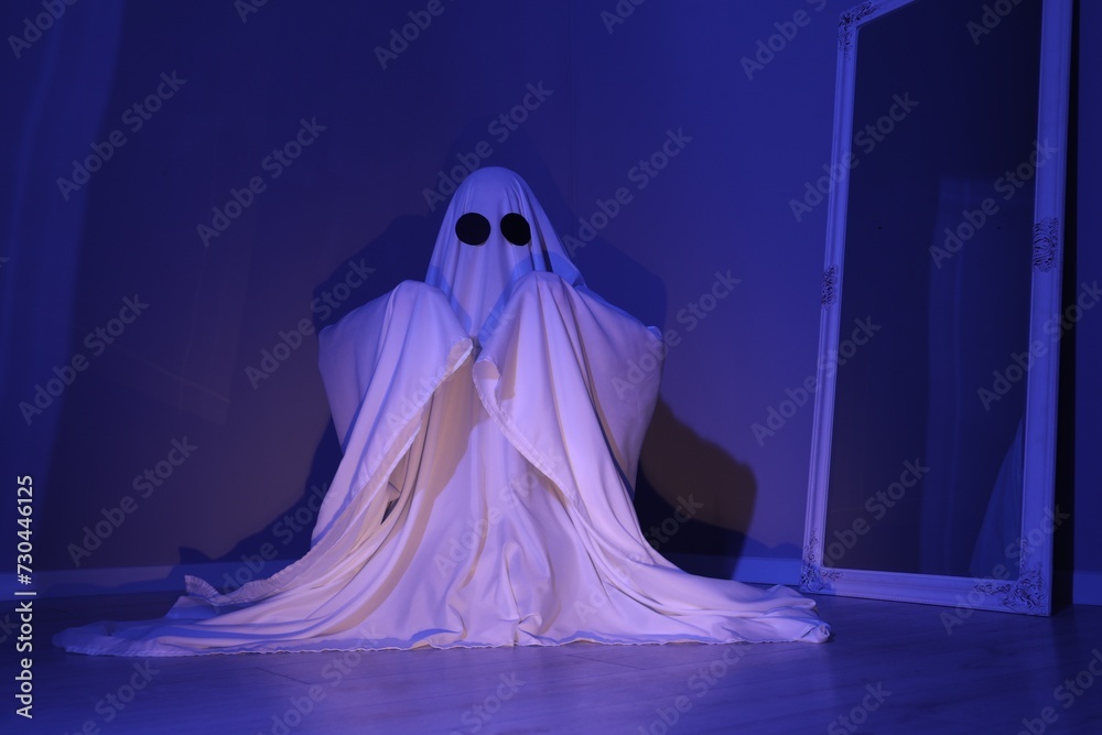 Creepy ghost. Woman covered with sheet in blue light Creepy ghost. Woman covered with sheet in blue light