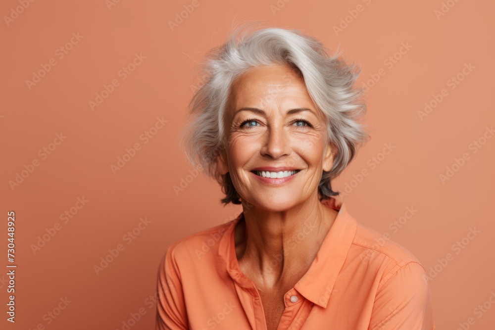 Happy senior woman with grey hair. Portrait of beautiful mature woman looking at camera and smiling while standing against brown background Happy senior woman with grey hair. Portrait of beautiful mature woman looking at camera and smiling while standing against brown background