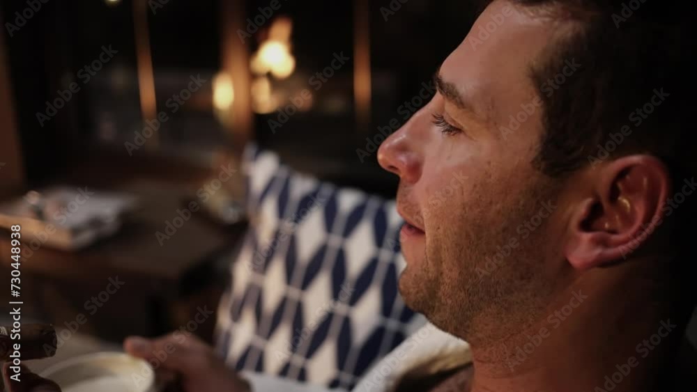 Adult man smokes cigar and drinks coffee near burning fire. Slow motion Adult man smokes cigar and drinks coffee near burning fire. Slow motion
