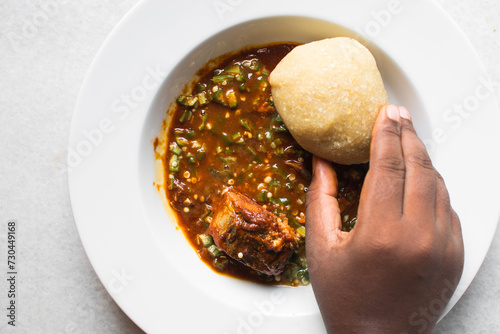 Nigerian okro and stew with eba in a white plate, top view of okro soup and eba