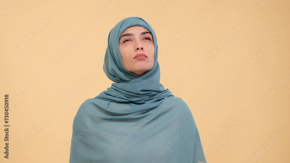 Serious and confused Arab woman thinking, finding solution to problem, making decision, planning on beige background. Thoughtful lady, question, dilemma concept. Serious and confused Arab woman thinking, finding solution to problem, making decision, planning on beige background. Thoughtful lady, question, dilemma concept.
