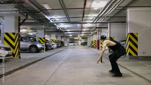 Young man jumps with salto over rolling wheel in underground garage. Slow motion photo