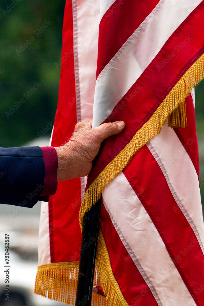 Vertical close-up of male hand holding an American flag commemorating Memorial Day in the United States of America. Vertical close-up of male hand holding an American flag commemorating Memorial Day in the United States of America.