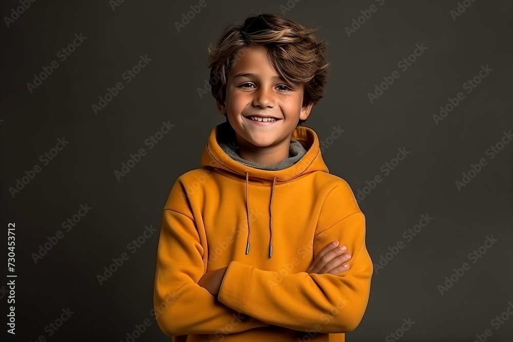 Portrait of a cute little boy in a yellow hoodie on a dark background Portrait of a cute little boy in a yellow hoodie on a dark background