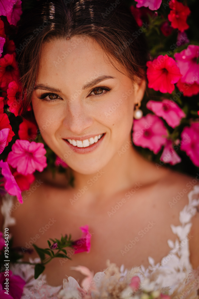 Valmiera, Latvia - July 7, 2023 - Bride smiling amidst vibrant pink flowers, bridal gown visible Valmiera, Latvia - July 7, 2023 - Bride smiling amidst vibrant pink flowers, bridal gown visible