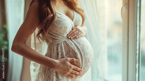 Close-up of joyful pregnant woman, big belly by the window, pregnancy and expectation theme