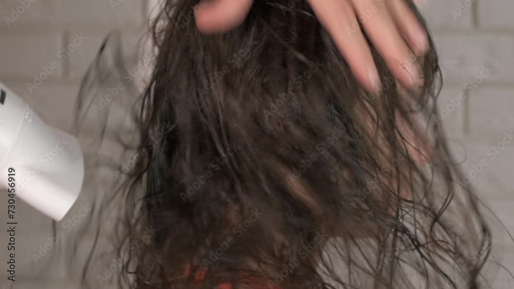 Female hands dry daughter long hair. A woman dry long girl hair with blow dryer indoor. Female hands dry daughter long hair. A woman dry long girl hair with blow dryer indoor.