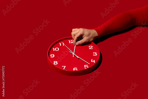 Adjusting time on a red wall clock photo
