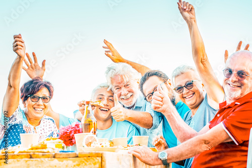 Multigenerational family having lunch on a terrace on a beautiful sunny day. 18 year old boy laughs with his grandparents celebrating. Lifestyle and family concept.​